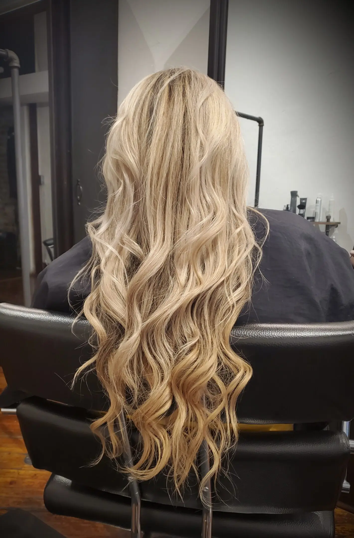 A woman with long blonde hair sitting in front of a mirror.