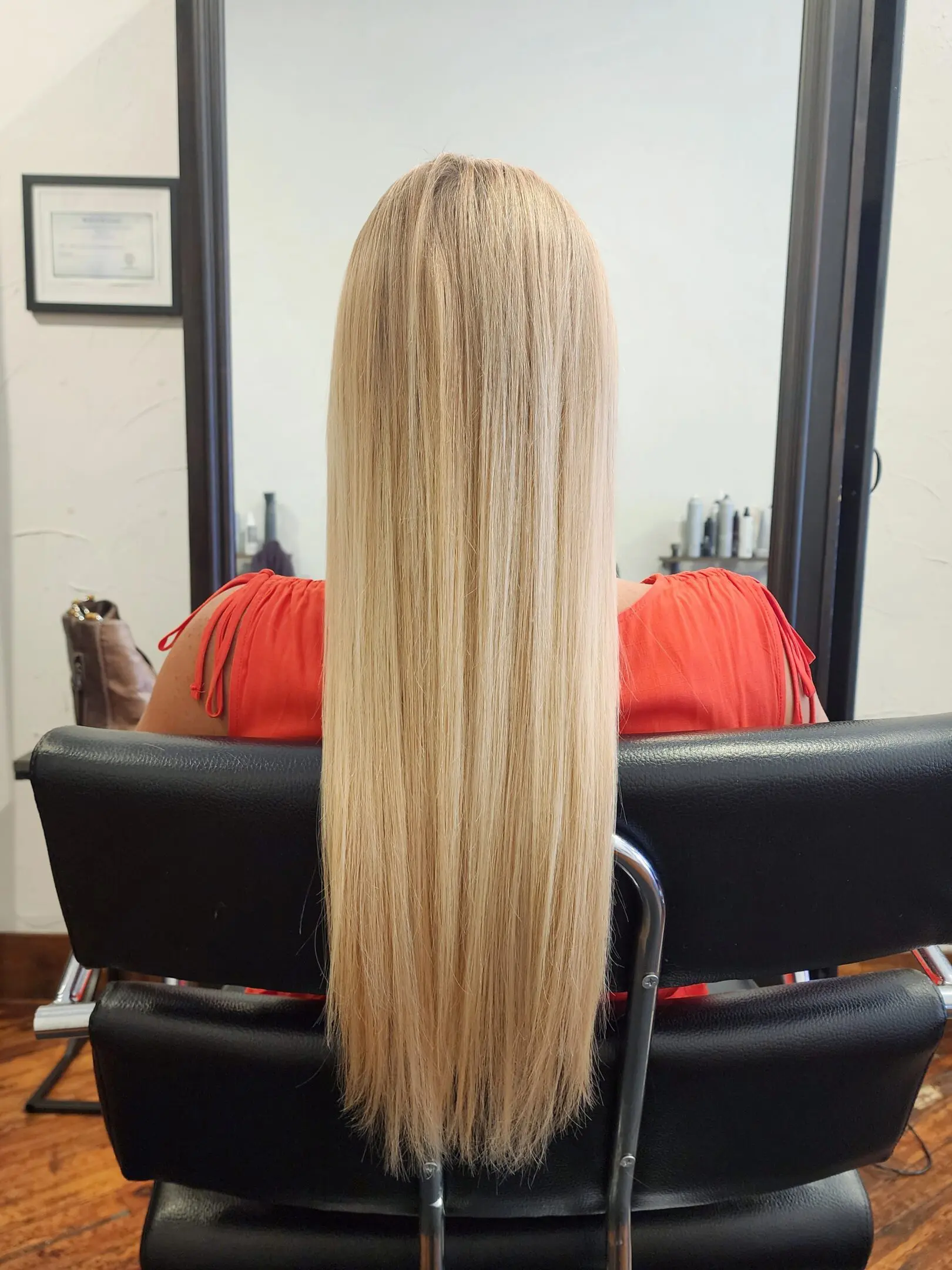 A woman sitting in front of a mirror with long blonde hair.