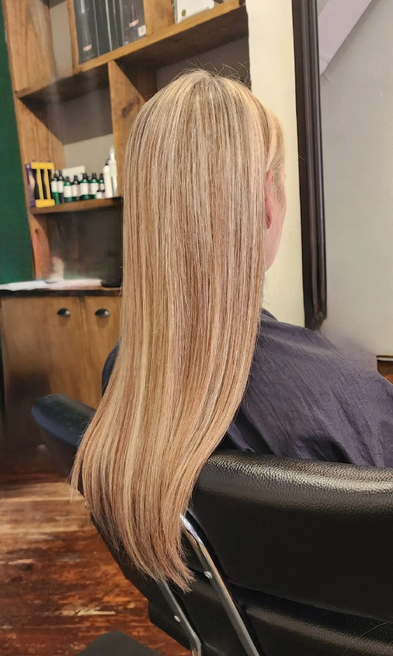 A woman sitting in front of a mirror with long blonde hair.