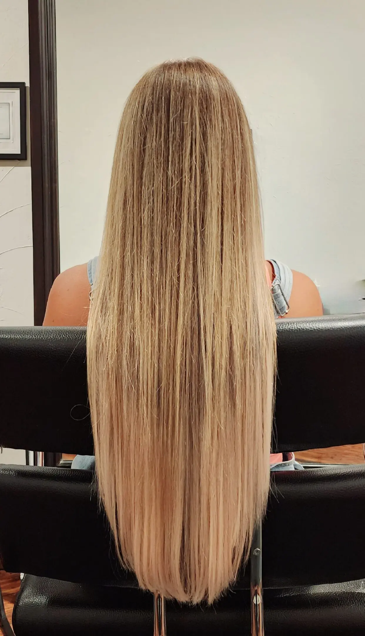 A woman sitting in front of a mirror with long blonde hair.