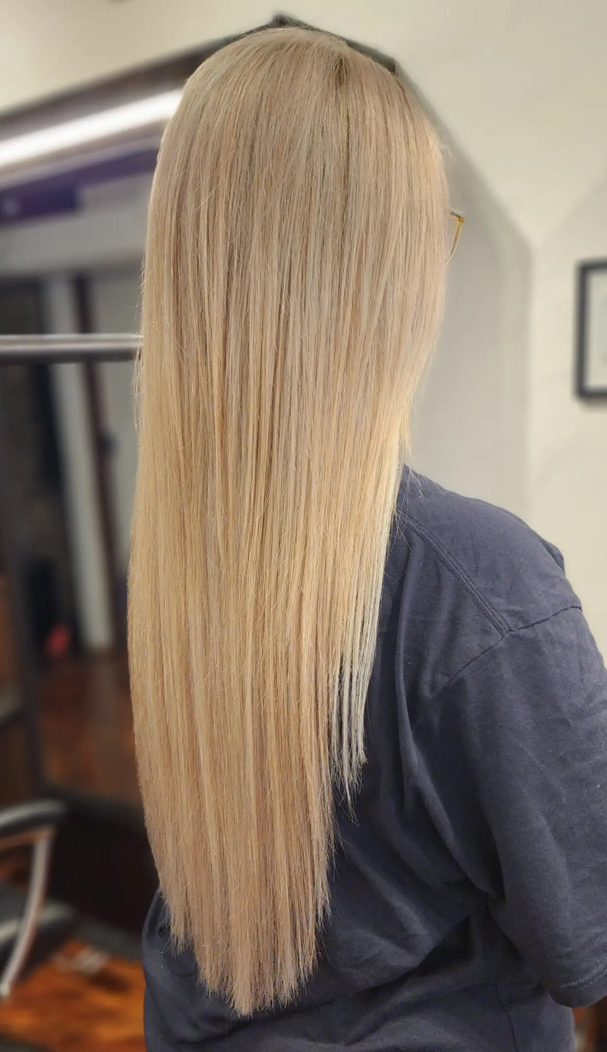 A woman with long blonde hair is standing in front of a mirror.