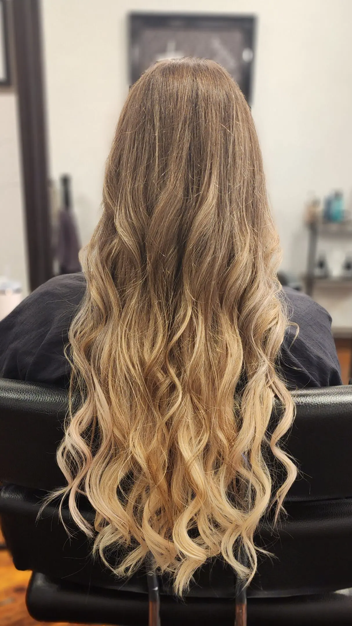 A woman sitting in front of a mirror with long hair.