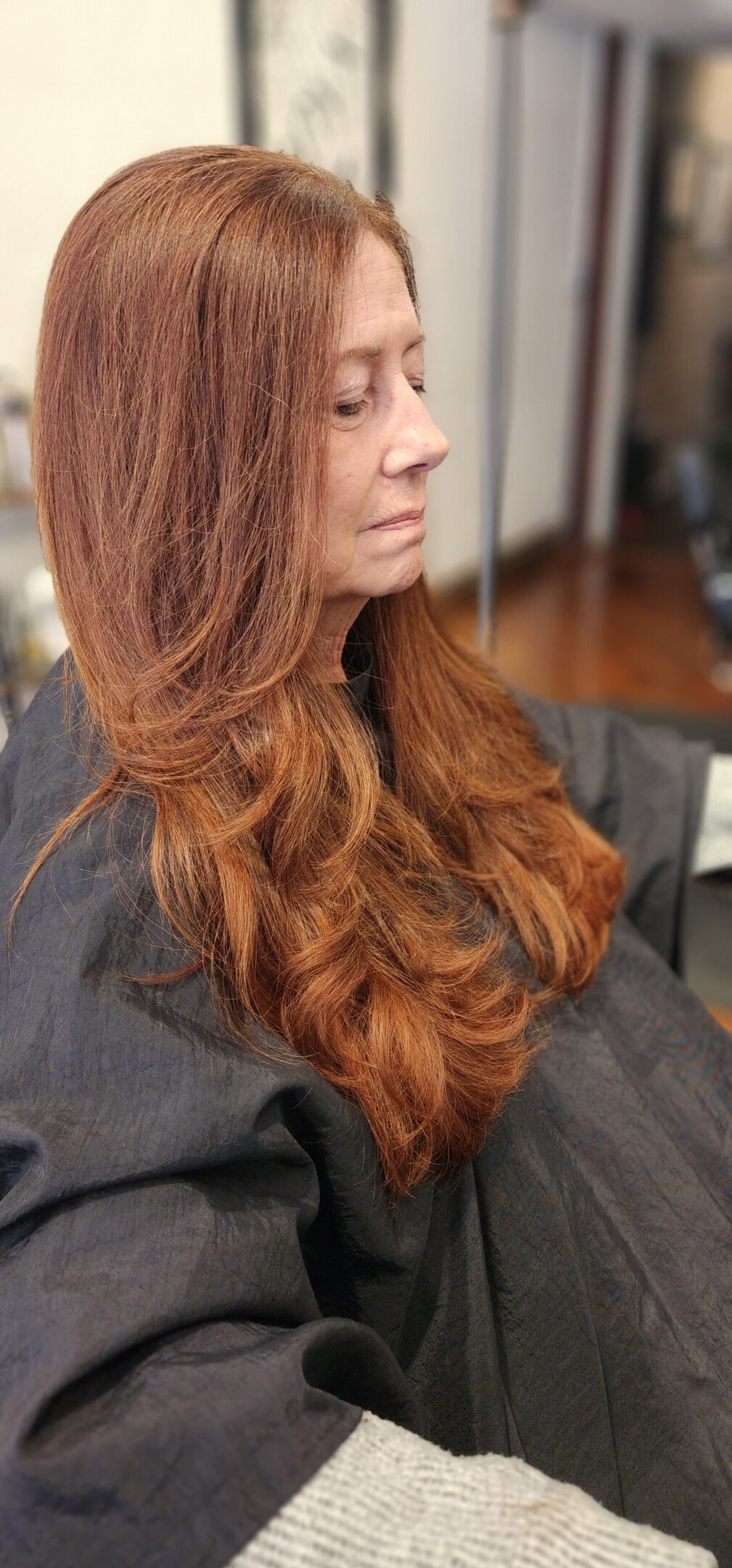 A woman with long red hair sitting in front of a mirror.