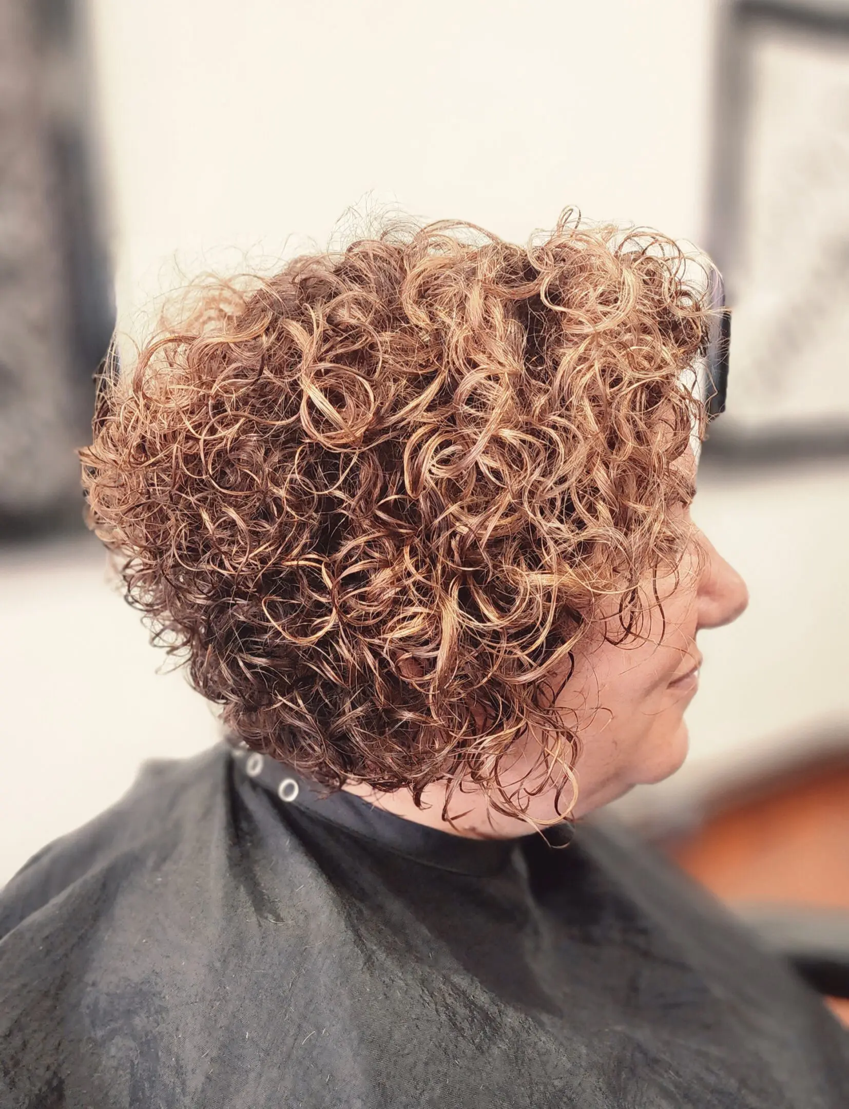 A woman with curly hair sitting in front of a mirror.