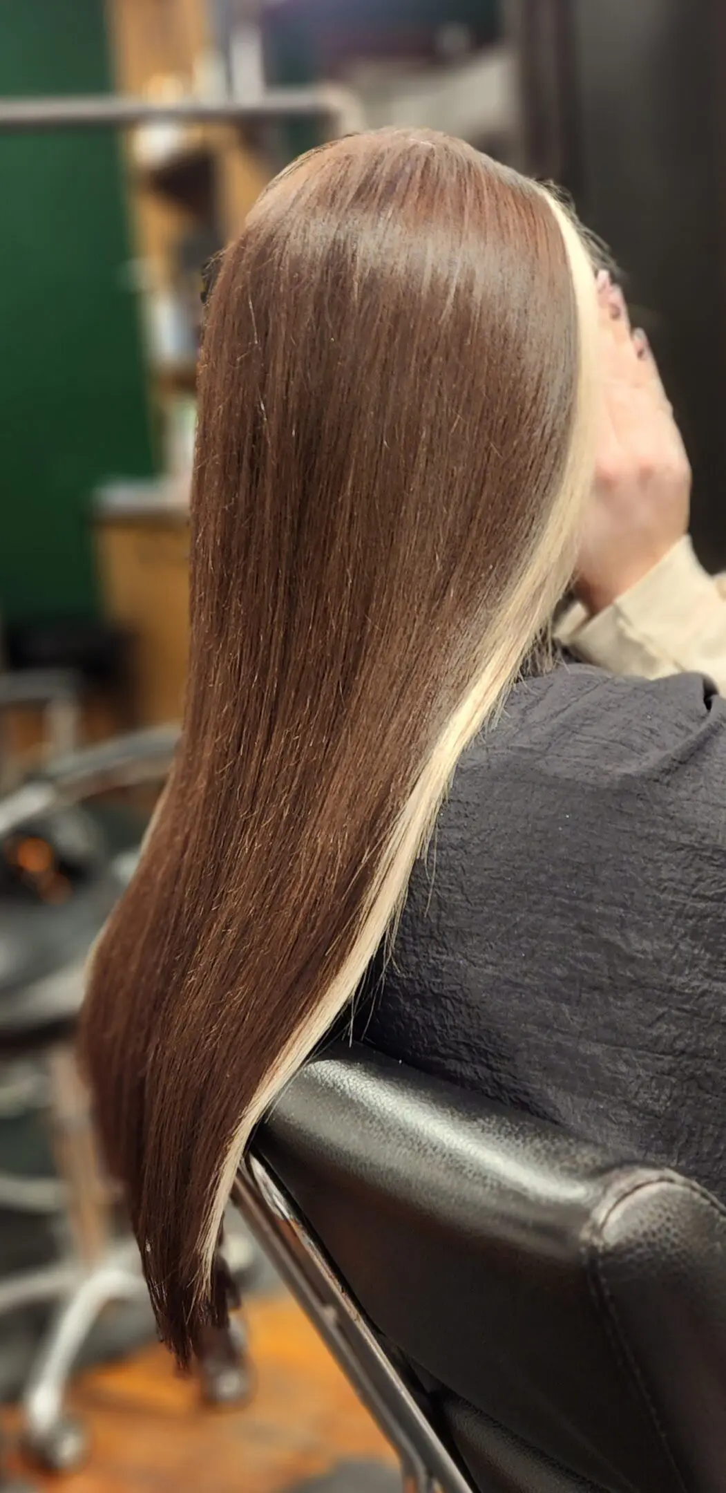 A woman sitting in front of a mirror with long hair.