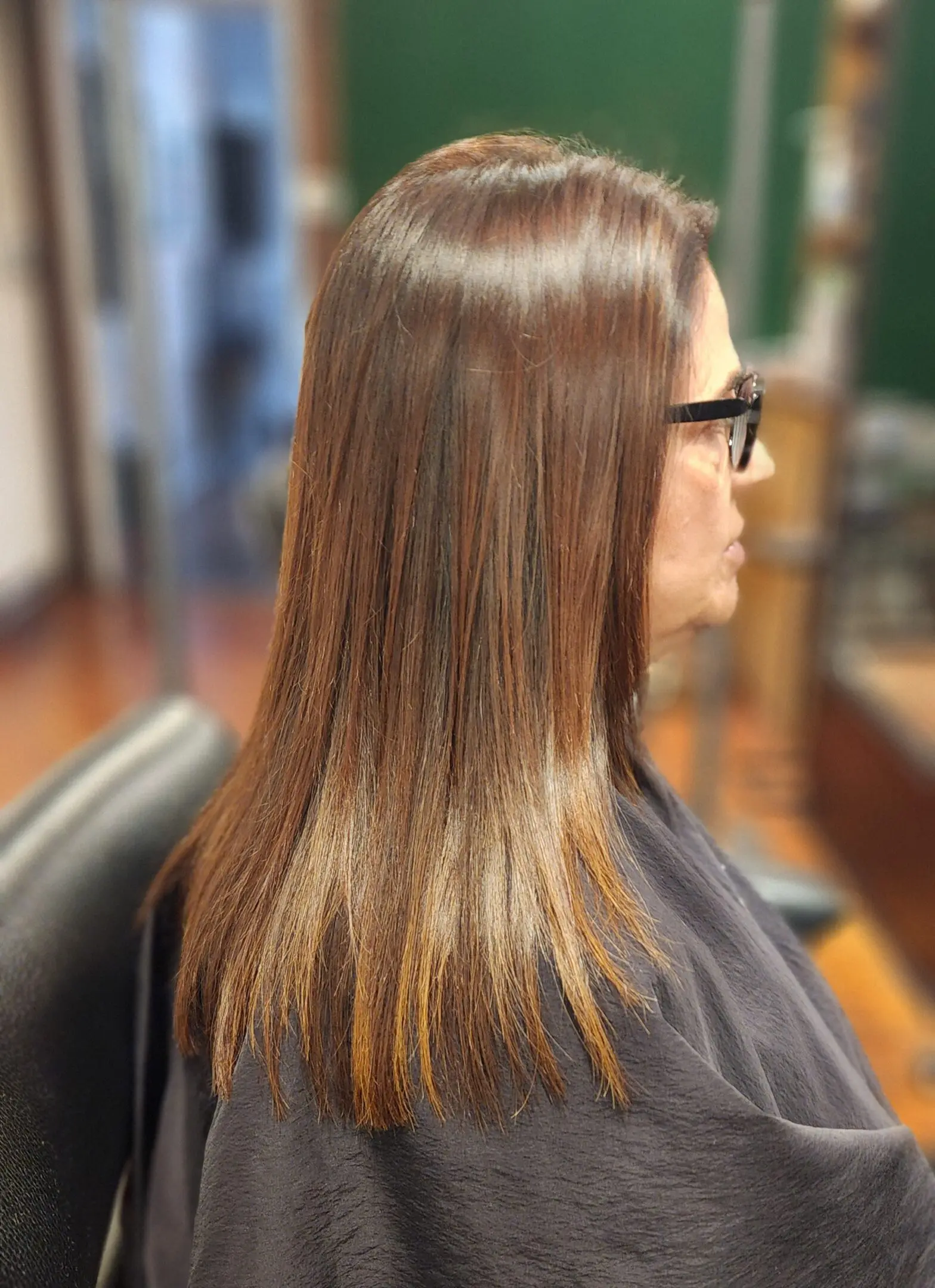 A woman with long hair sitting in front of a chair.