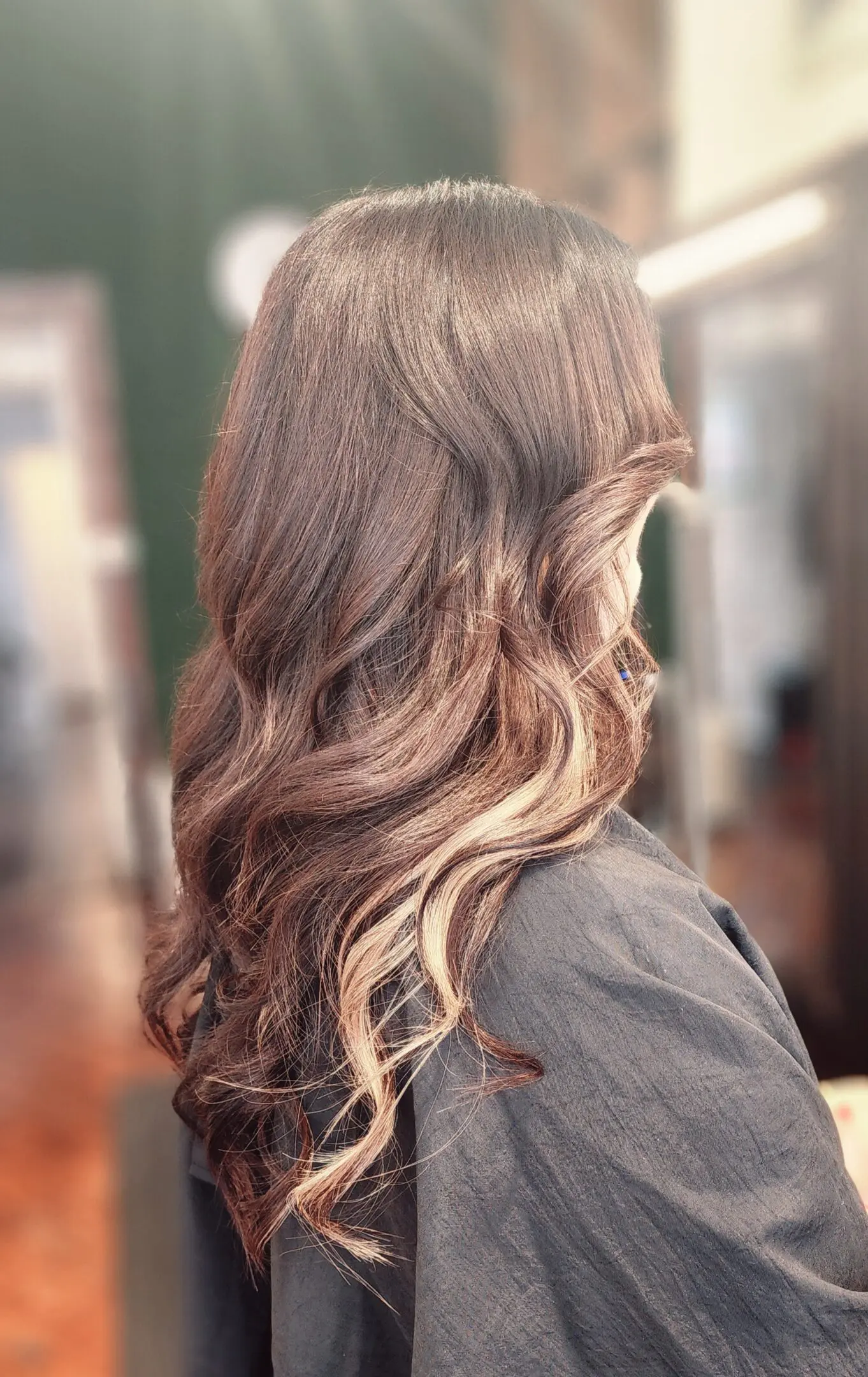 A woman with long hair is standing in front of mirrors.